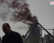 邯郸市永年县永洋钢铁厂炼铁炉倒入铁矿时冒出的褐色浓烟。杜刘固村的村民韩京财在菜地里扎菜，离炼铁炉只有一百多米。他的双手粘满了炼铁炉飘过来的黑乎乎的污染物。